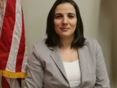A photo of Purchasing Agent Simona Casian-Sirbu next to the American flag.